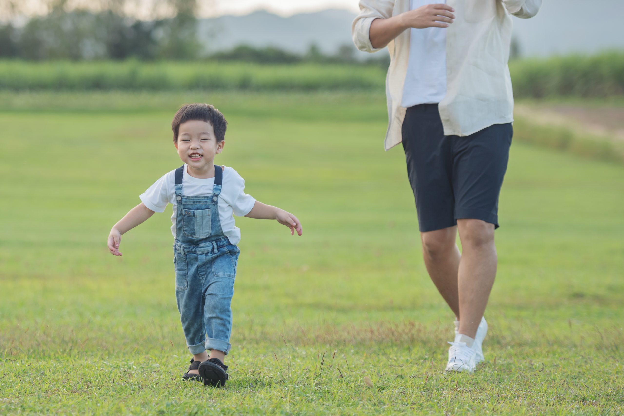 father son playing park sunset time people having fun field concept friendly family summer vacation father son legs walk across lawn park scaled